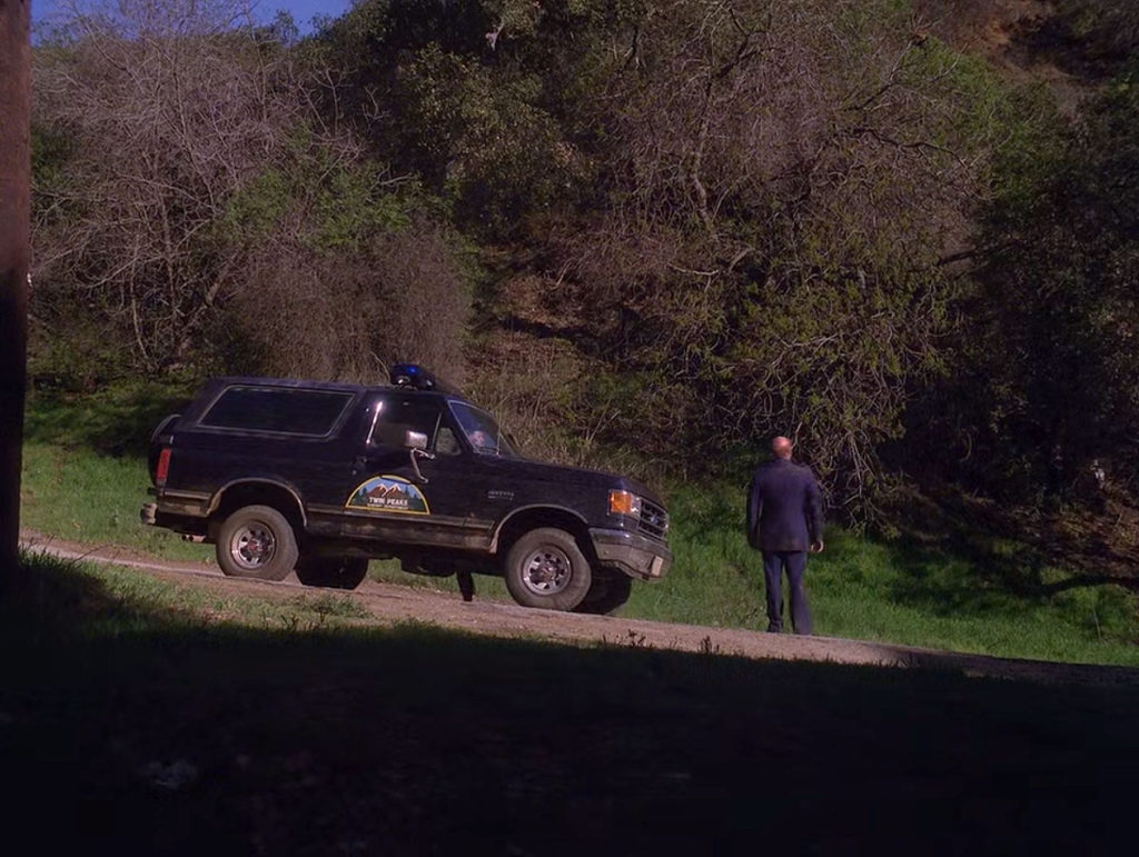 Hawk stops his car as Major Briggs walks onto the road.